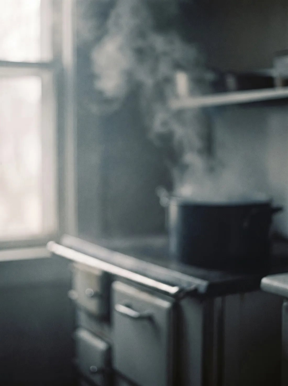 A half-remembered kitchen: steam rising over an old stove in soft window light.