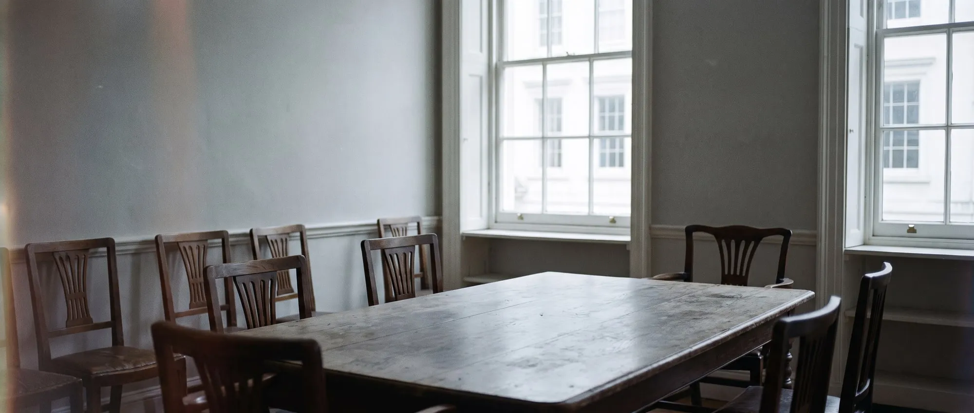 An empty Georgian meeting room in soft morning light, a long wooden table waiting for lunch.